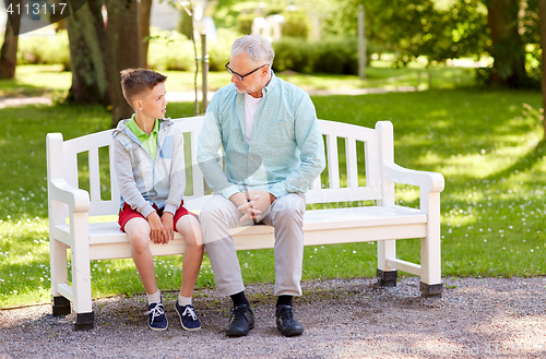 Image of grandfather and grandson talking at summer park