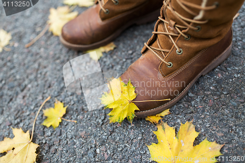 Image of female feet in boots and autumn leaves