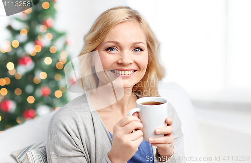 Image of smiling woman with cup of tea or coffee at home