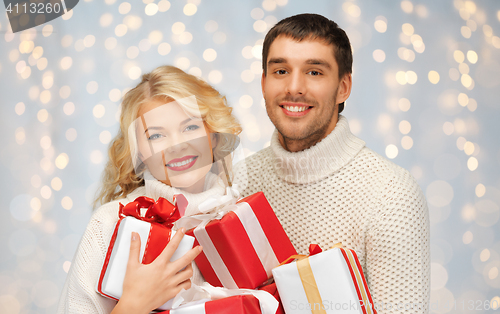 Image of smiling man and woman with presents over lights