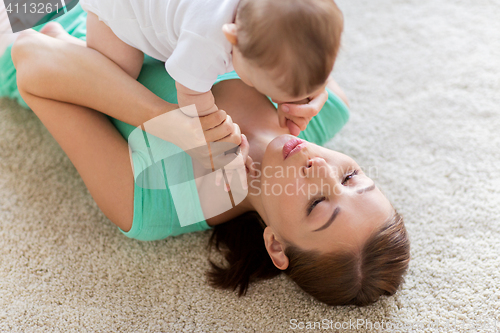 Image of happy mother playing with little baby at home