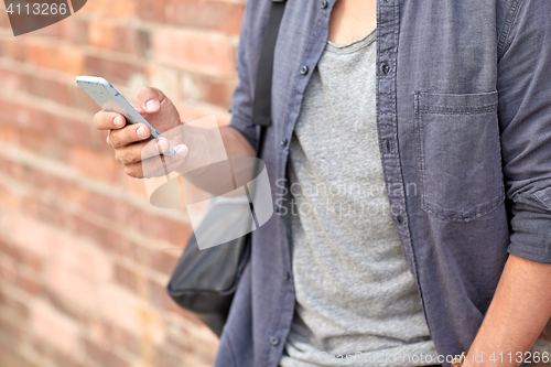 Image of close up of man texting on smartphone in city