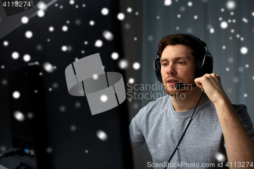 Image of man in headset playing computer video game at home