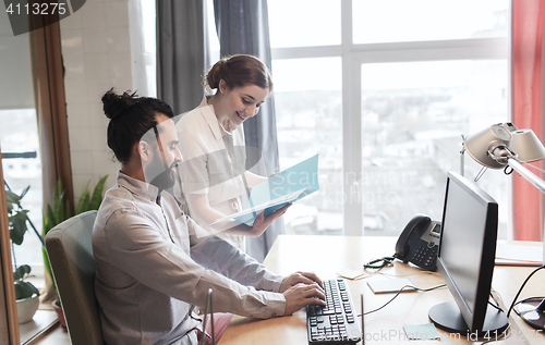 Image of happy creative team with computer in office