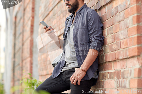 Image of close up of man texting on smartphone in city