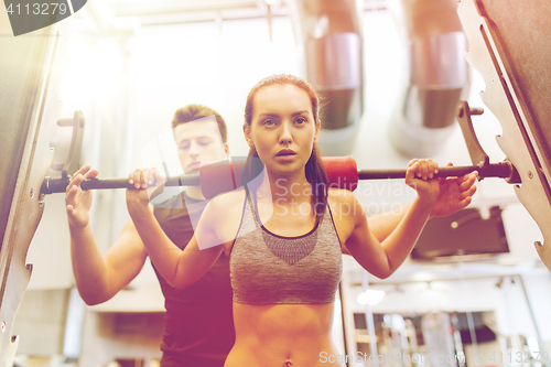 Image of man and woman with barbell flexing muscles in gym