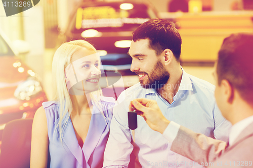 Image of happy couple with car dealer in auto show or salon