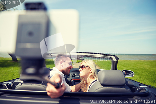 Image of happy couple in car taking selfie with smartphone