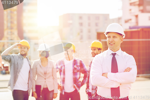 Image of group of smiling builders in hardhats outdoors