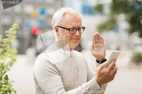 Image of senior man having video call on smartphone in city