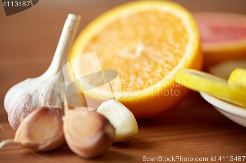 Image of close up of garlic and orange on wooden table