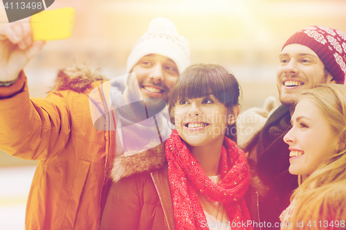 Image of happy friends taking selfie on skating rink