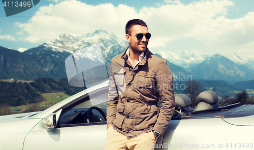 Image of happy man near cabriolet car over mountains