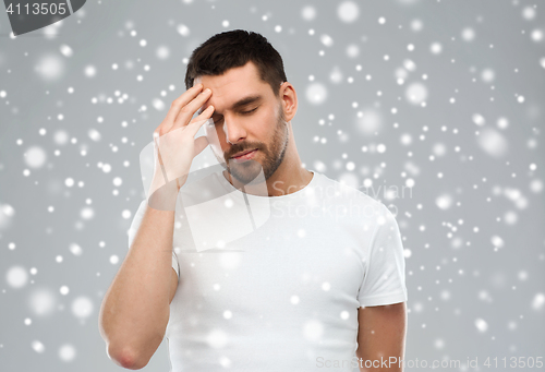 Image of young man suffering from headache over snow