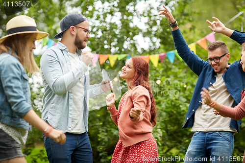 Image of happy friends dancing at summer party in garden
