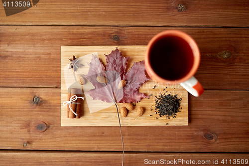 Image of cup of tea, maple leaf and almond on wooden board