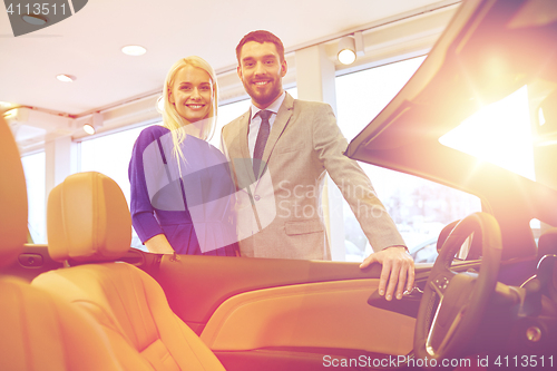 Image of happy couple buying car in auto show or salon