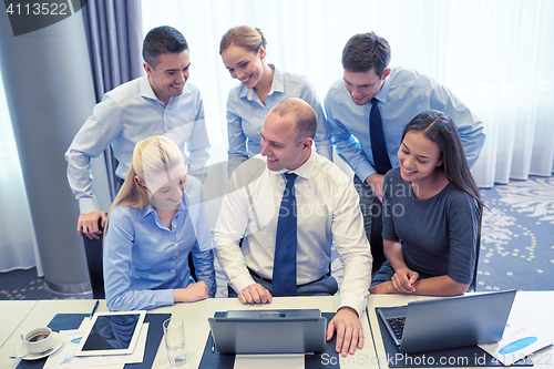 Image of smiling business people with laptop in office