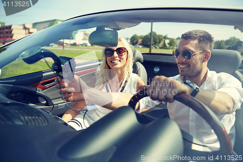 Image of happy couple using gps navigator in cabriolet car
