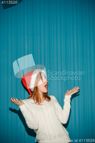 Image of Surprised christmas girl wearing a santa hat