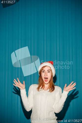 Image of Surprised christmas girl wearing a santa hat