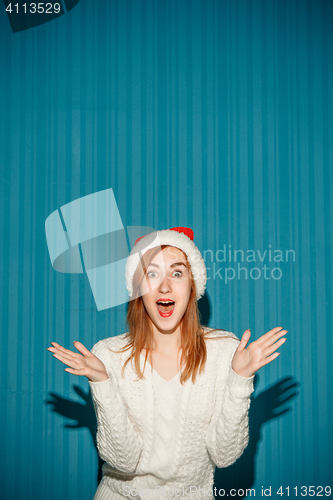 Image of Surprised christmas girl wearing a santa hat