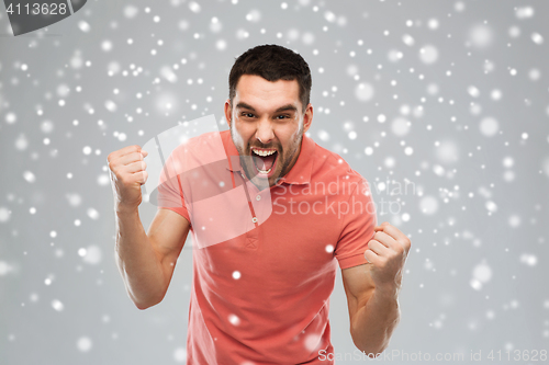 Image of angry young man holding fists over snow