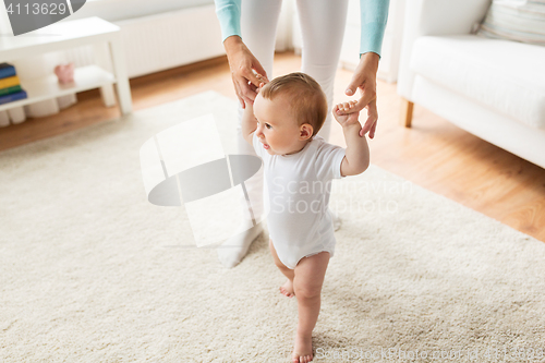 Image of happy baby learning to walk with mother help