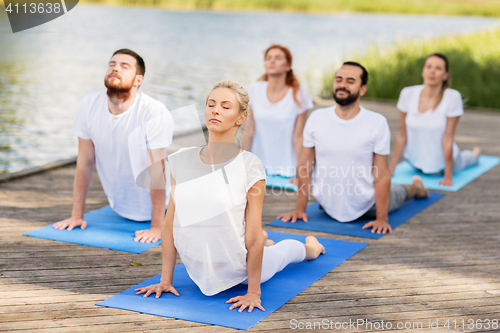 Image of group of people making yoga exercises outdoors