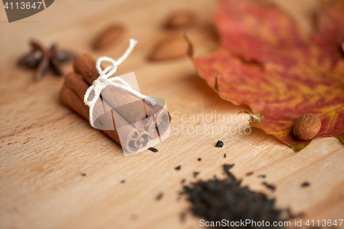 Image of cinnamon, maple leaf and almond on wooden board