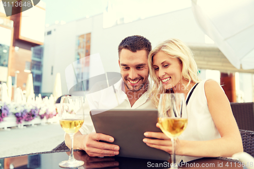 Image of happy couple with tablet pc at restaurant terrace