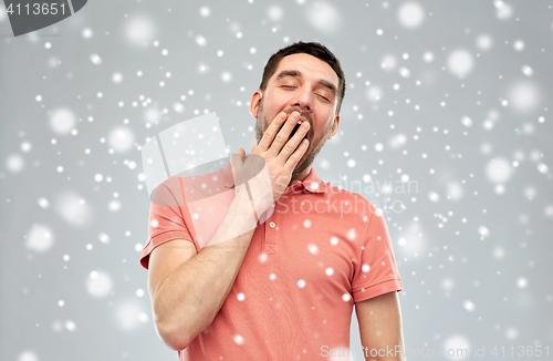 Image of tired yawning man over snow background