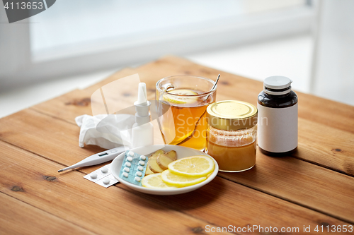 Image of drugs, thermometer, honey and cup of tea on wood