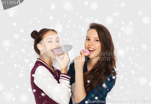 Image of happy pretty teenage girls eating donuts