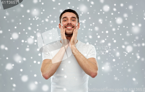 Image of happy man applying aftershave or cream to face