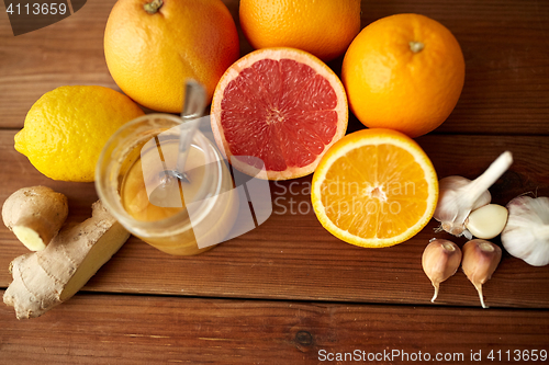 Image of honey, citrus fruits, ginger and garlic on wood