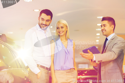 Image of happy couple with car dealer in auto show or salon