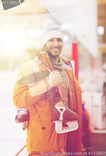 Image of happy young man with ice-skates on skating rink