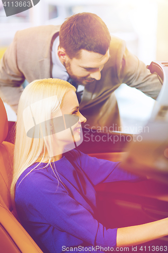 Image of happy couple buying car in auto show or salon
