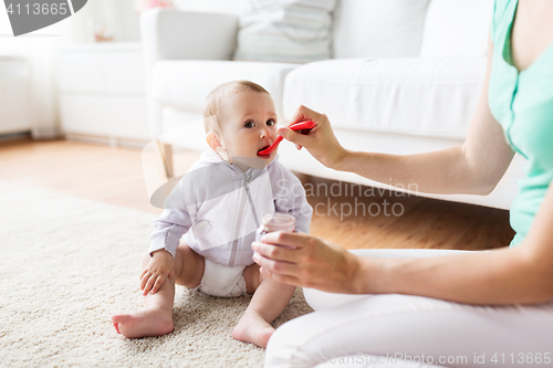 Image of mother with spoon feeding little baby at home