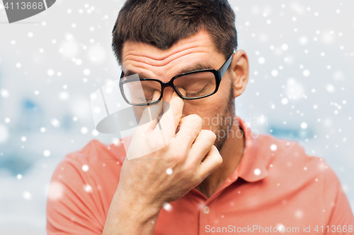 Image of close up of tired man in eyeglasses rubbing eyes