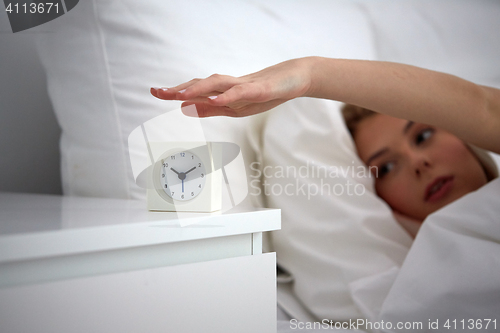 Image of close up of woman with alarm clock in bed at home