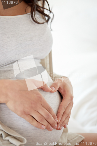 Image of close up of pregnant woman making heart gesture