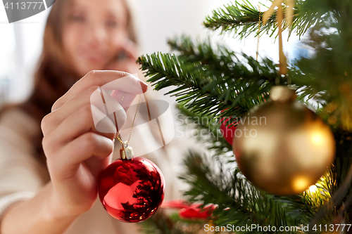 Image of happy young woman decorating christmas tree