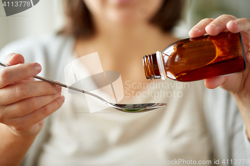 Image of woman pouring medication from bottle to spoon