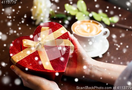 Image of close up of hands holding heart shaped gift box