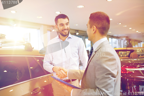 Image of happy man shaking hands in auto show or salon