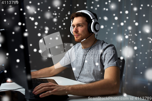 Image of man in headset playing computer video game at home