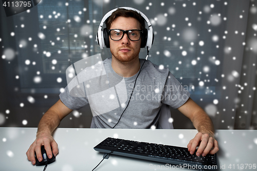 Image of man in headset playing computer video game at home