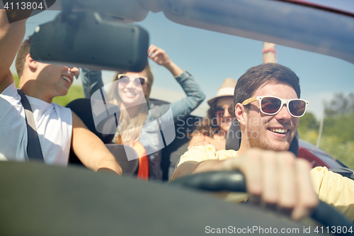 Image of happy friends driving in cabriolet car